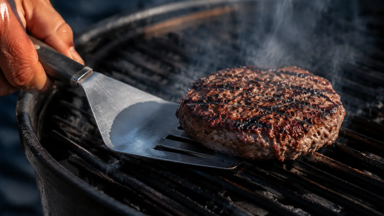 Backyard griller using a long-handled BBQ brush to baste chicken thighs on a pellet grill at golden hour